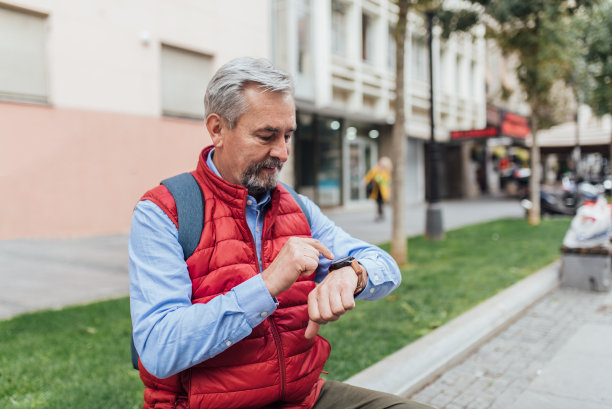 一位老人正在休息，看着他的手表图片下载