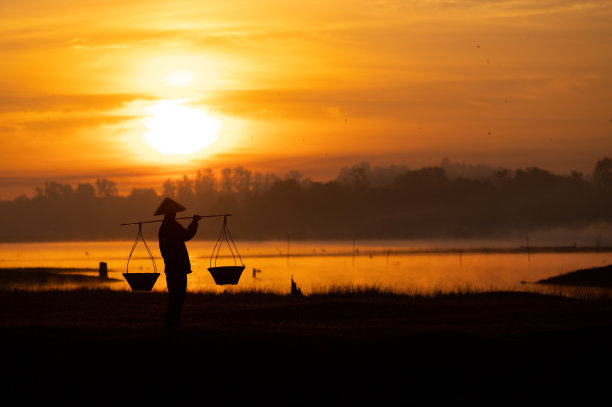 泰国农民正提着篮子准备在太阳下山前回家。轮廓农民。轮廓光。图片下载