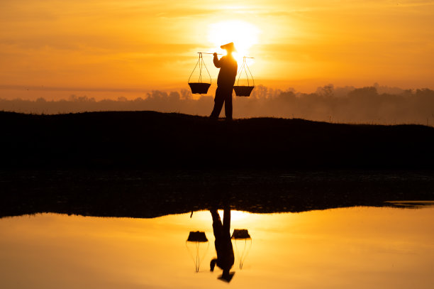 泰国农民正提着篮子准备在太阳下山前回家。轮廓农民。轮廓光。图片下载