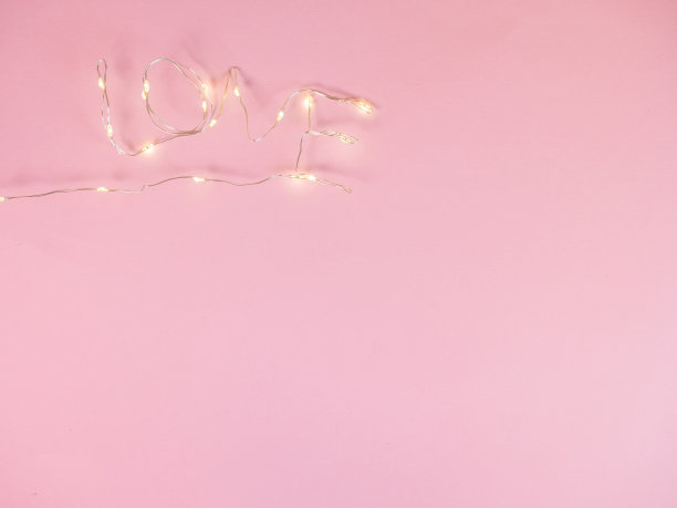 电灯把爱的文字放在粉红色的背景上图片下载