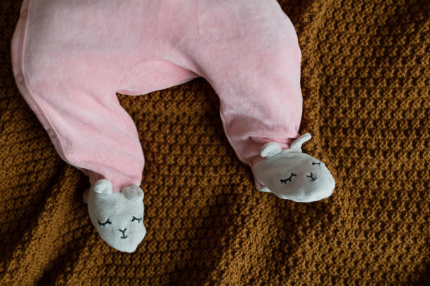 四个月大的金发白种人婴儿躺在舒适的针织毯子上。穿着可爱的粉红色衣服的孩子图片下载