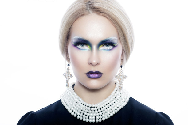 一个金发女孩的工作室肖像和时尚的化妆没有衣服和珍珠项链和十字耳环。图片下载