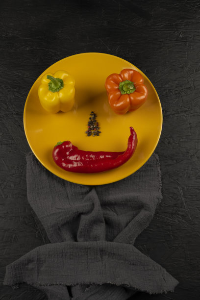 新鲜美味，黄色，红色和橙色的辣椒在黑色的背景图片下载