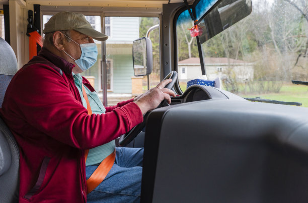 新冠肺炎大流行期间，戴着医用口罩驾驶校车的老人在农村地区。图片下载