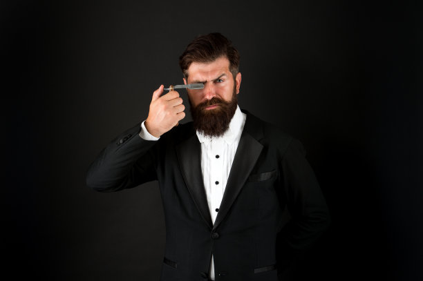 保持野蛮。长着胡子，一脸凶相的男人。残忍的商人手持剃刀。潮人不刮胡子的脸总是锋利的。理发店。理发店。美发沙龙。残酷的和有胡子的图片下载