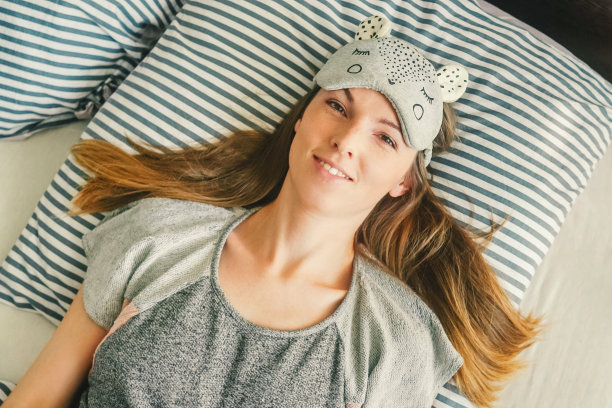 一个年轻女子在床上伸懒腰。醒来。图片下载