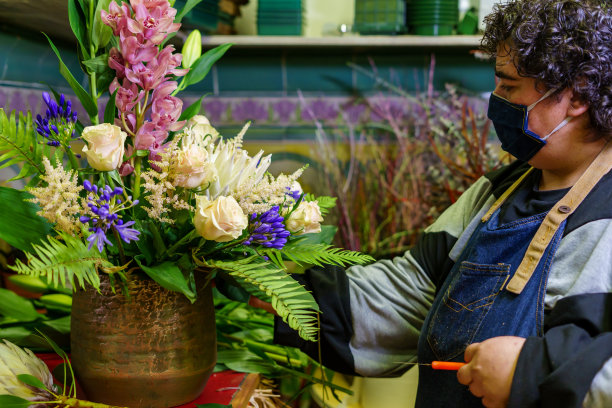 一家花店的老板正在处理一束花后重新开放的新冠肺炎图片下载