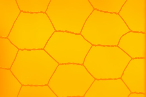 鲜艳的黄色背景与钢栅栏，网眼图案图片下载