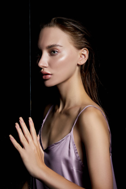 美丽的女人，湿漉漉的头发靠近玻璃在雨点。天然化妆品和化妆品图片下载