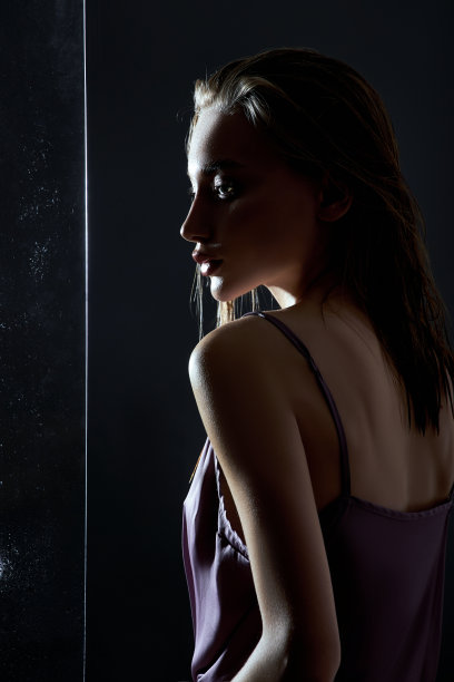 美丽的女人，湿漉漉的头发靠近玻璃在雨点。天然化妆品和化妆品图片下载