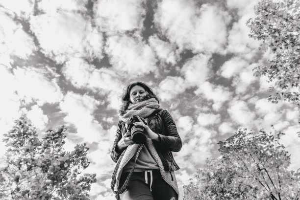 女孩摄影师以天空和无数云彩为背景。图片下载