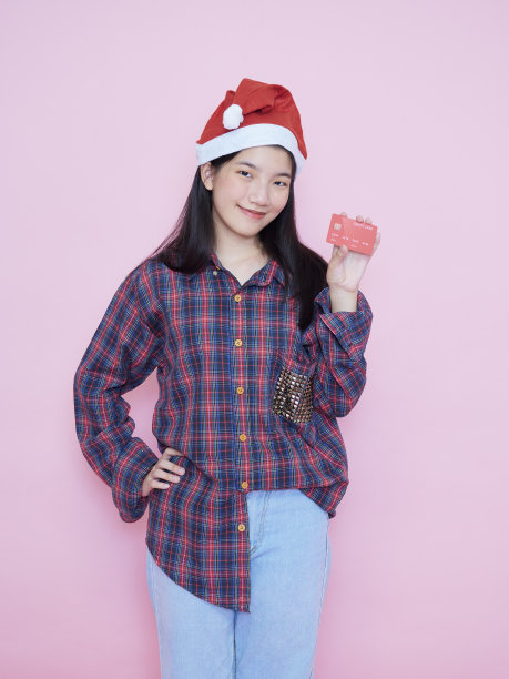 快乐的年轻女子戴着圣诞老人帽，上面显示着信用卡图片下载