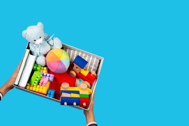 捐赠的概念。孩子的手与捐赠箱，衣服，书籍和玩具在浅蓝色的背景。俯视图图片下载