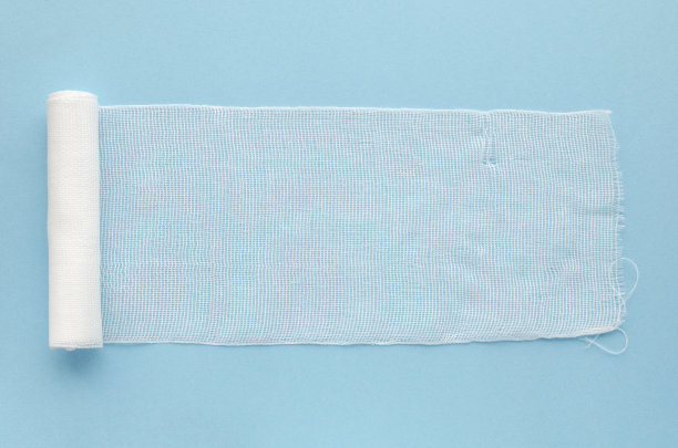无菌绷带，蓝色背景，俯视图，拷贝空间。白色医用棉绷带，蓝色背景，复制空间。白色棉布绷带孤立在蓝色背景，俯视图。图片下载