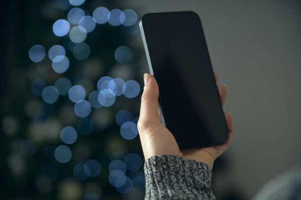 一名年轻女子在自己的客厅里用智能手机与朋友进行在线社交、祝福和庆祝。图片下载