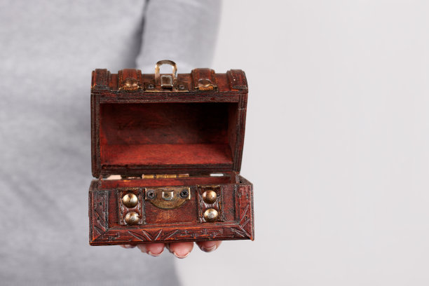 手与木制的箱子在灰色的背景。图片下载