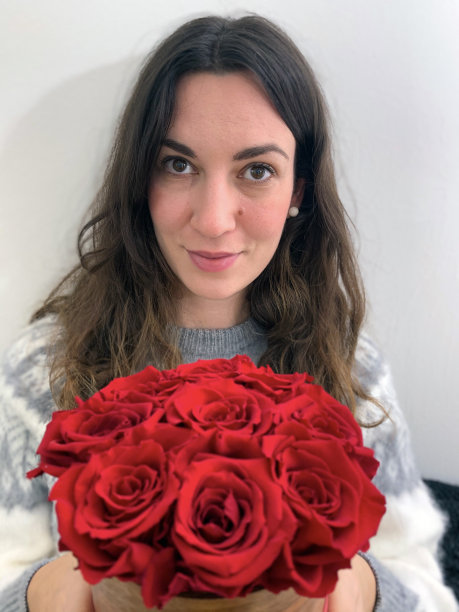 年轻女子捧着美丽的红玫瑰花束图片下载