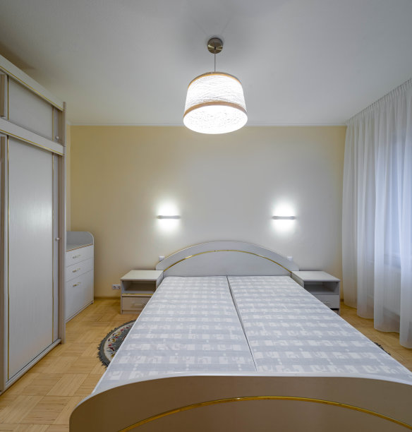 现代室内灯光卧室在豪华公寓。舒适的床的正面视图。白色的梳妆台和衣柜。图片下载