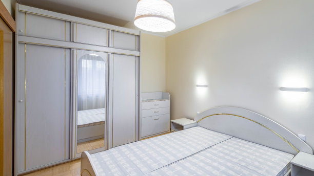 公寓卧室的现代内饰。带镜子的推拉门衣柜。白色的梳妆台、床和床头柜。图片下载