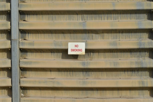 禁止吸烟标志上的金属，褐色纹理的墙壁。图片下载