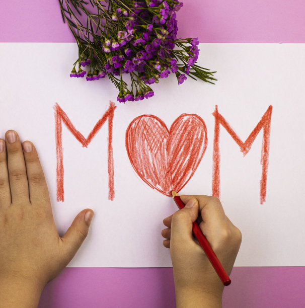 双手用红色铅笔为妈妈做母亲节卡片，俯视图图片下载