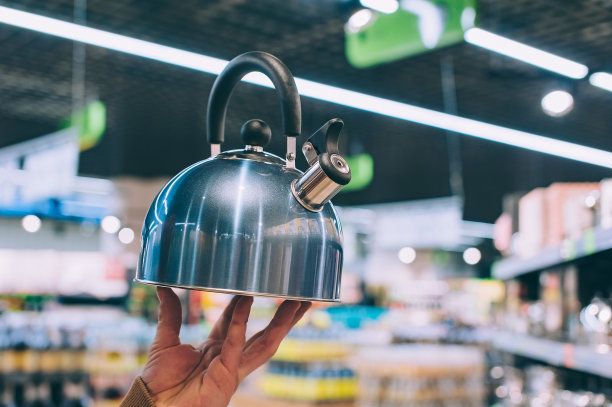 一个男人在超市里拿着一个金属水壶。图片下载