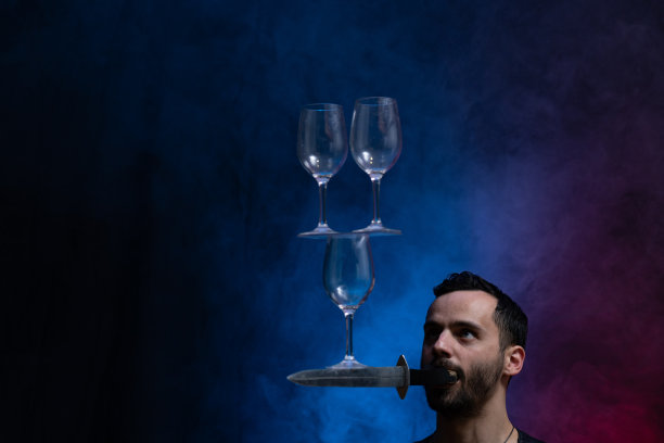 男人嘴里衔着刀，嘴里还放着酒杯保持平衡。浓度图片下载
