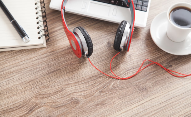 红色耳机，咖啡，电脑键盘，笔和笔记本放在木桌上。图片下载