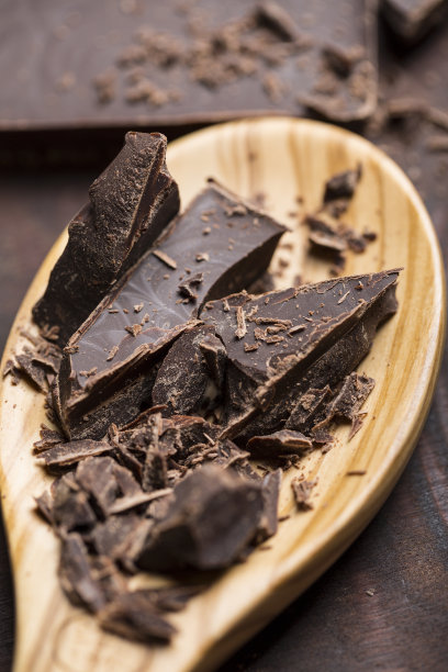 木勺与芳香的黑巧克力刨花烘烤在木制背景，近距离图片下载