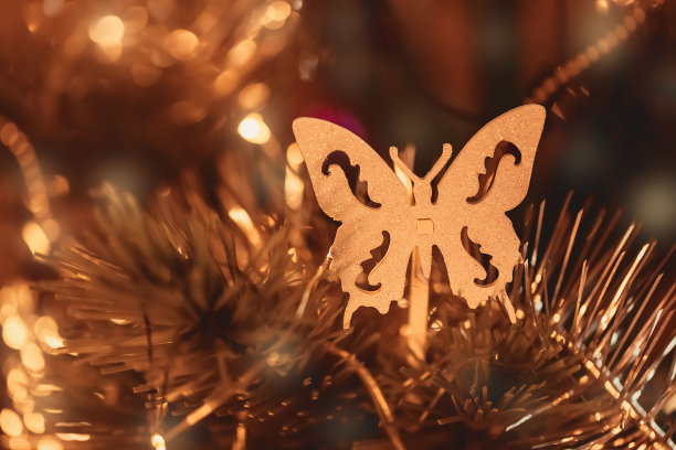 金色的圣诞树玩具的形式的蝴蝶，金箔和闪亮的花环在黑暗的背景。新2021年。有选择性的重点。副本的空间。墙纸。图片下载