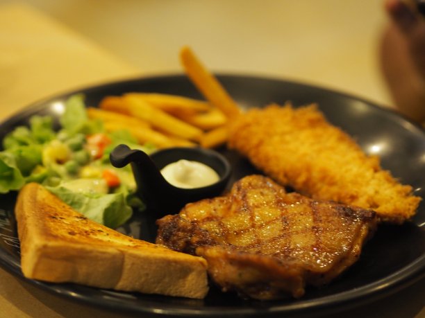 黑胡椒鸡配蔬菜沙拉，吐司和炸薯条放在黑色盘子里烹调食用图片下载