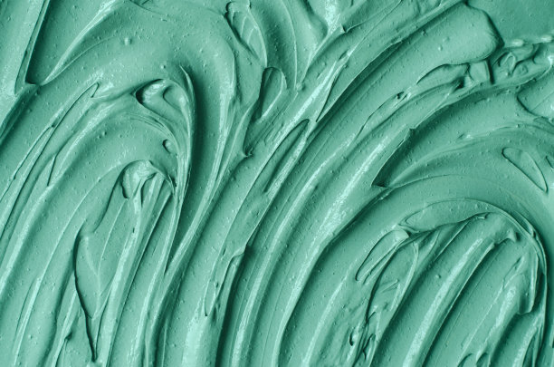 绿色化妆粘土(海带面膜、面霜、螺旋藻体贴)质地近距离，选择性聚焦。抽象的背景与画笔笔触。图片下载
