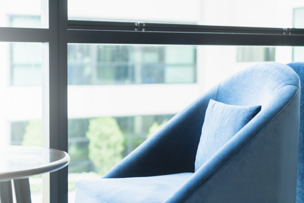 靠近窗户的蓝色面料扶手椅和咖啡桌与来自外部的光线现代办公室设计图片下载