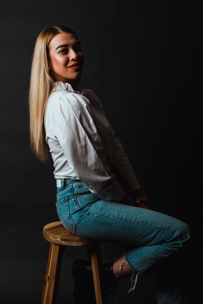 穿着白衬衫和牛仔裤的女人坐在酒吧的木凳上图片下载