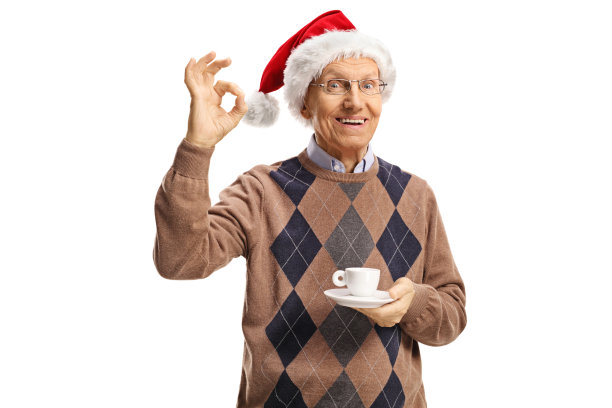 一个老人拿着一杯咖啡，戴着圣诞老人的帽子，做了一个完美的手势图片下载