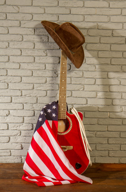 一顶传统的宽边牛仔帽，一把古典木吉他上挂着美国星条旗图片下载