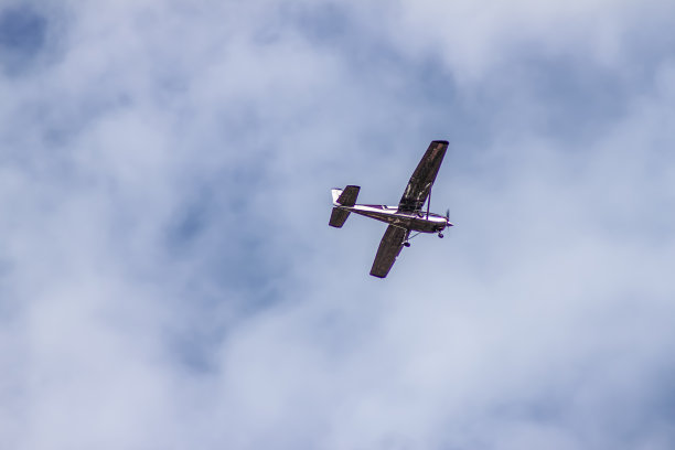 螺旋桨飞机在斑驳多云的蓝天上空飞行图片下载