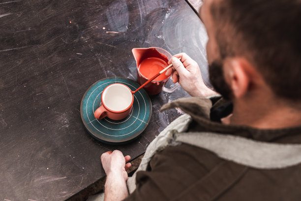 专业的陶工或装饰师在陶艺工坊或工作室绘制红色陶土杯，手工制作，艺术品和手工概念图片下载