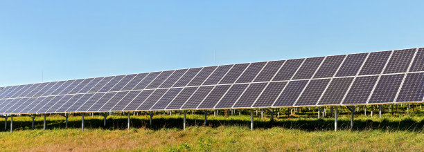 太阳能光伏板上绿色的草地，晴朗的天空，宽幅的横幅照片图片下载