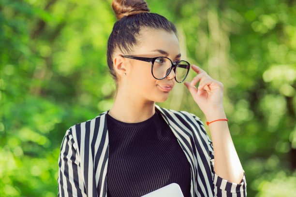 妻子将信将疑地望向一边，带着笔记本电脑在一个城市公园的绿色自然背景下图片下载