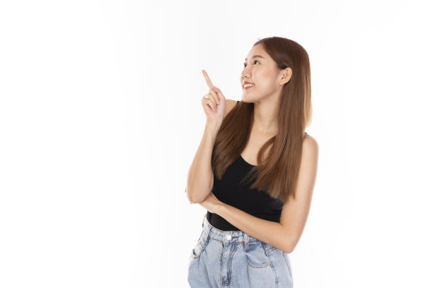 肖像年轻美丽的亚洲女人幸福的微笑在孤立的白色背景。美丽的亚洲女孩微笑，与手签名和复制空间。随便的女人，亚洲学生在白色的背景下微笑，看起来很开心。图片下载