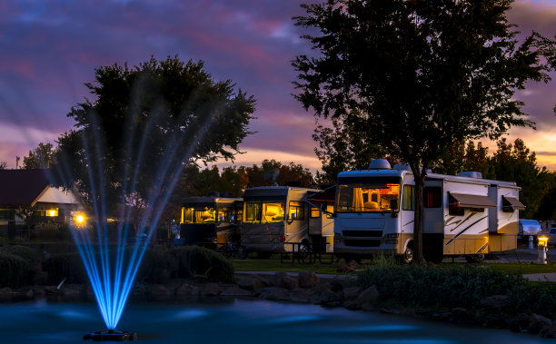 在a级钻机上的灯光下，在日落的天空下，在水塘与一个彩色的喷泉图片下载