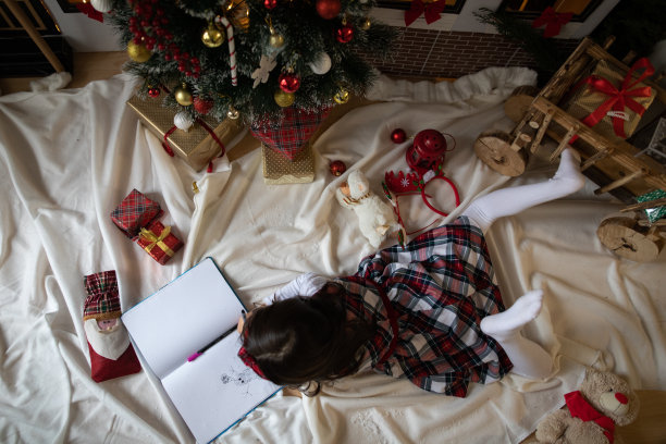 女孩躺在圣诞树前，在家画画，享受着元旦图片下载