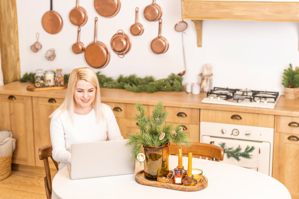 微笑的女人坐在家里的笔记本电脑上上网，图片下载