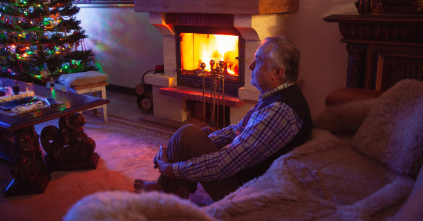 在黑暗的房间里，一位老人坐在壁炉前图片下载