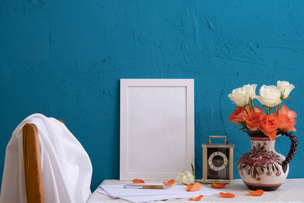 古董钟，旧花瓶里的一束玫瑰，写字用的一套，桌上蓝色背景上的照片用的白色相框图片下载