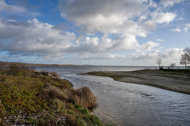 从一个湖泊的河流出口与一个戏剧性的天空在背景。图片来自瑞典斯卡尼亚的呕吐湖图片下载