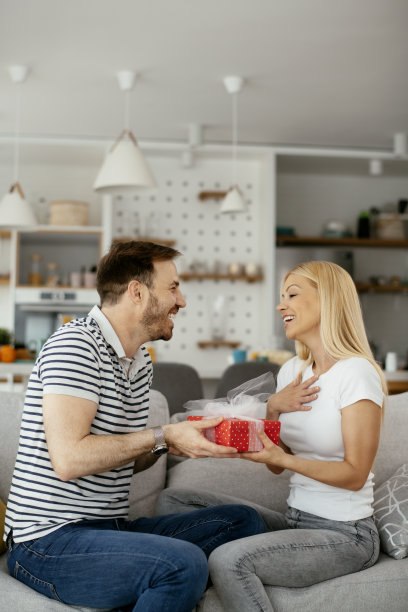 一个男人用礼物给他的女朋友一个惊喜。库存图片图片下载