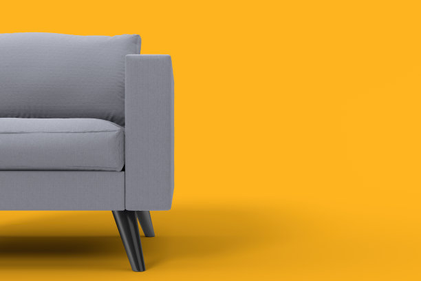 带枕头的灰色扶手椅，背景是工作室的黄色。图片下载