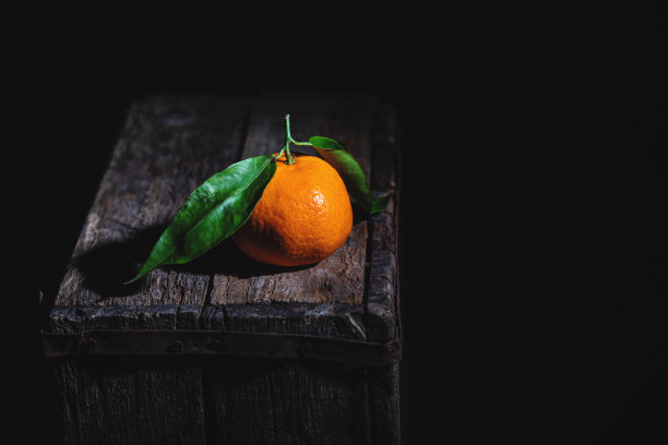 橘子和叶子在一个旧木箱上。低调的摄影。图片下载